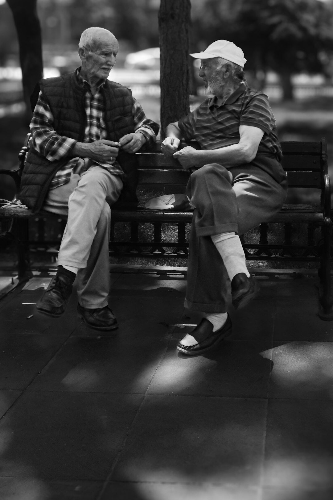 Two seniors sitting on a park bench having a friendly conversation